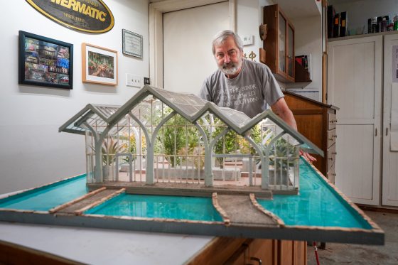 A person standing behind a model of the new glass Conservatory at Longwood Gardens. 